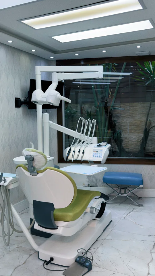 Cadeira e equipamentos odontológicos em sala com divisória de vidro