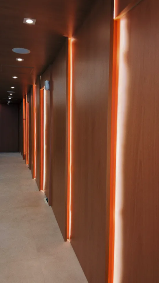 Corredor escuro marcado por linhas verticais de luz âmbar