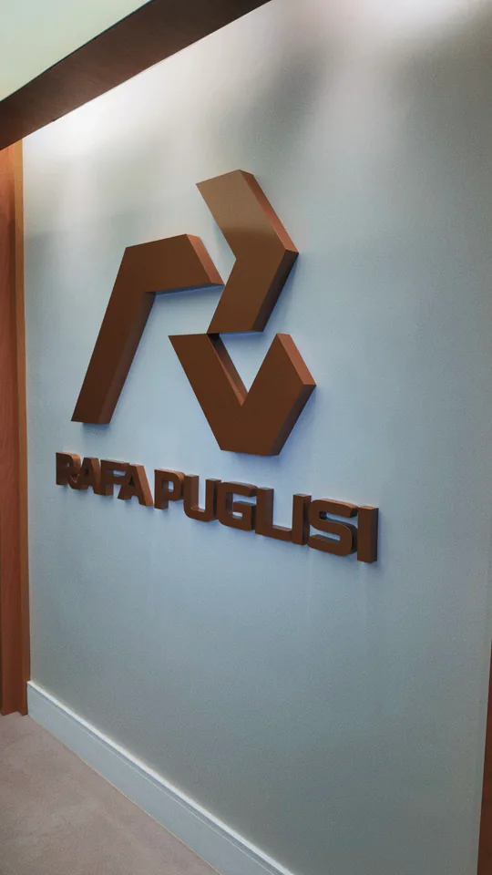 Marca Rafa Puglisi aplicada em uma parede clara do corredor