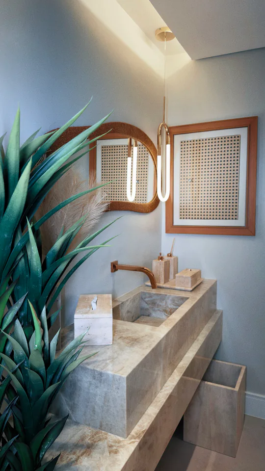 Lavabo com bancada de pedra, espelho iluminado e plantas