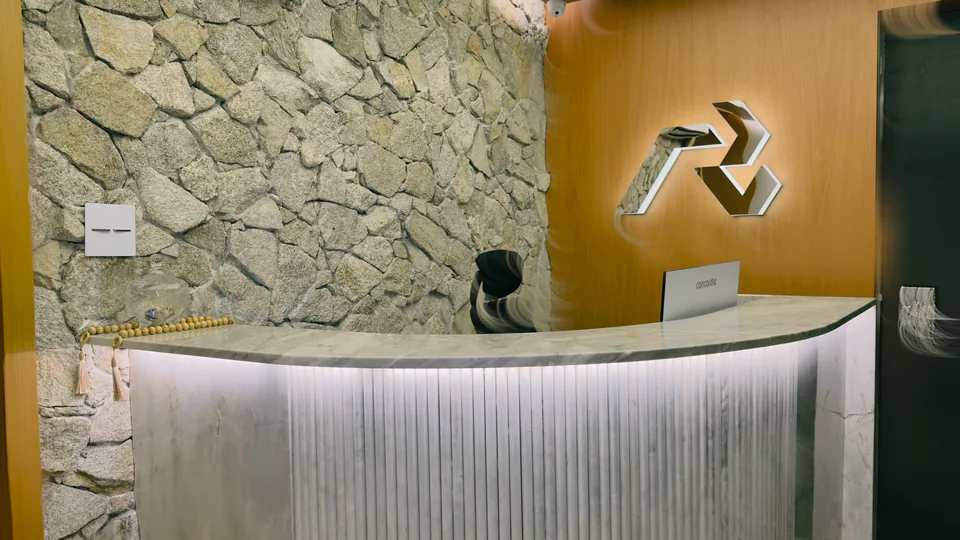 Balcão da recepção com iluminação inferior e materiais naturais