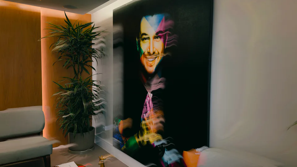 Retrato artístico de Rafa Puglisi ao lado de uma planta e mesa