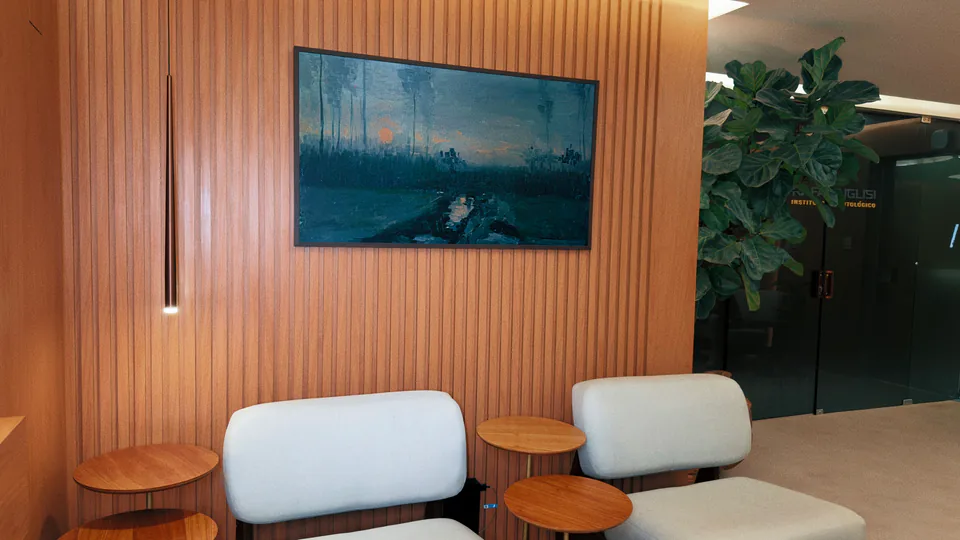Sala de espera com poltronas claras, mesas e painel de madeira