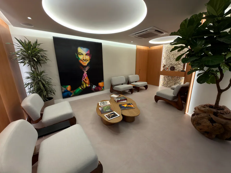 Vista ampla da sala de espera com retrato de Rafa Puglisi, poltronas claras e vegetação