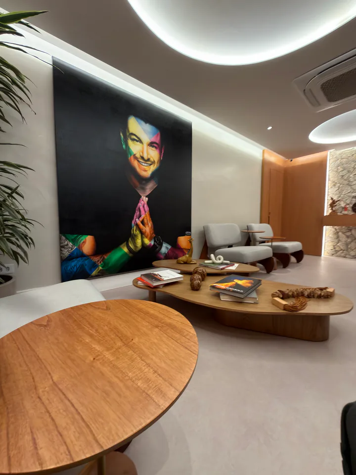 Sala de espera atual do Instituto com retrato de Rafa Puglisi, poltronas e mesas de madeira