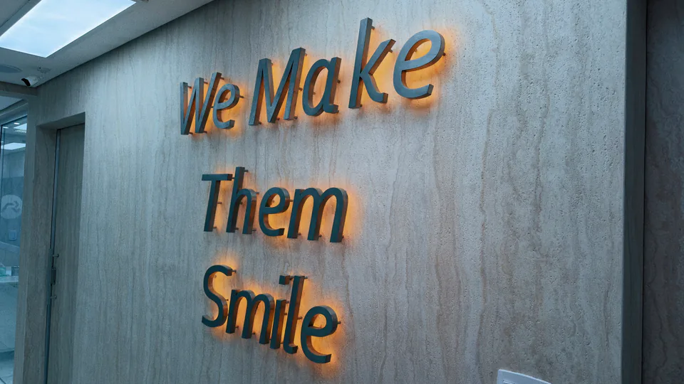Frase We Make Them Smile em relevo sobre parede de pedra