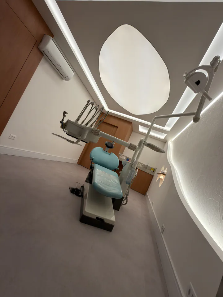 Enquadramento vertical do consultório com cadeira azul e luminária odontológica