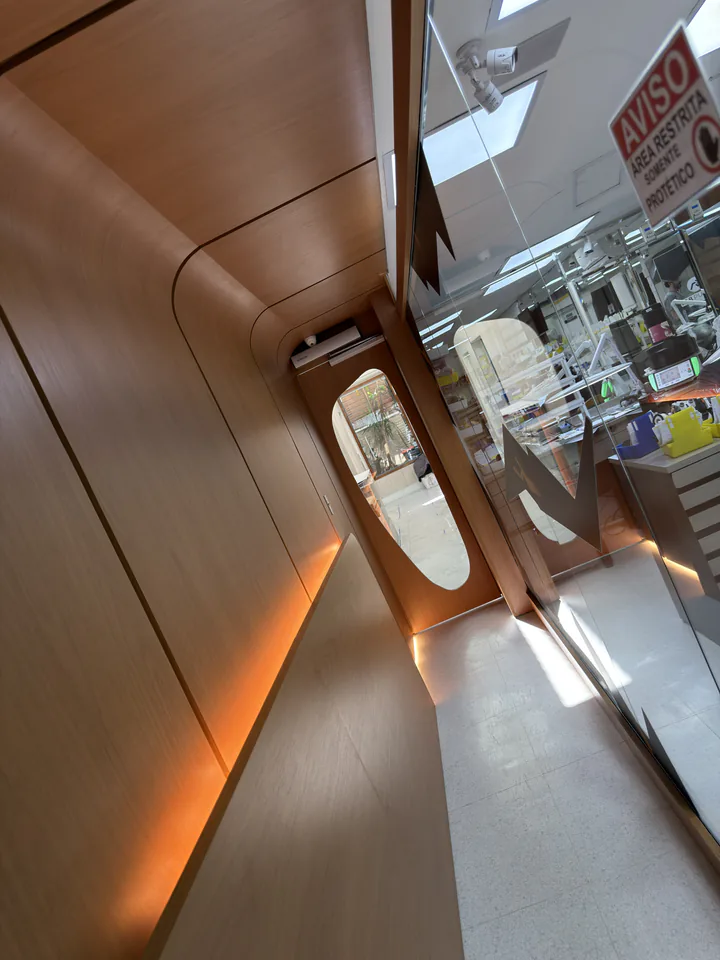 Corredor curvo com painel de madeira, iluminação âmbar e porta ao fundo