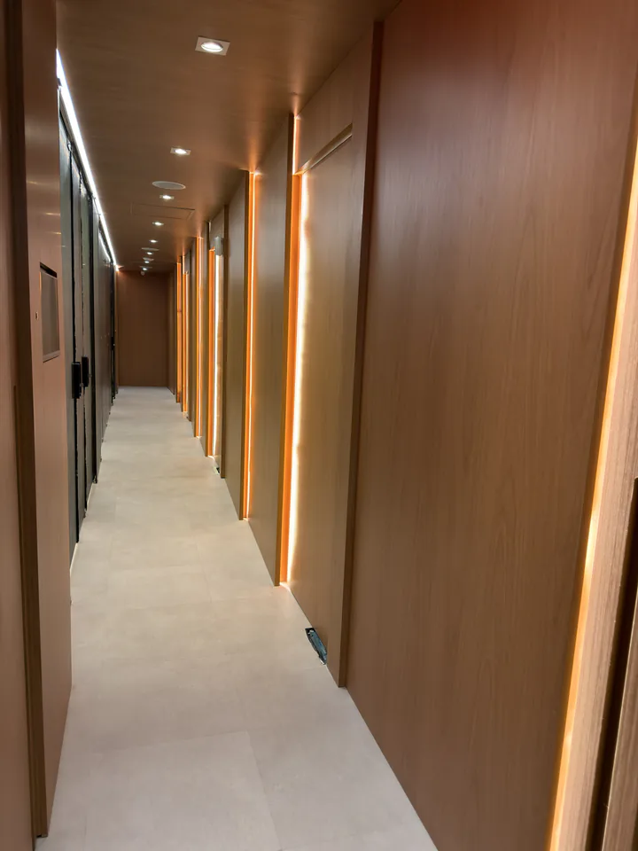 Corredor longo com portas de madeira e linhas verticais de luz âmbar