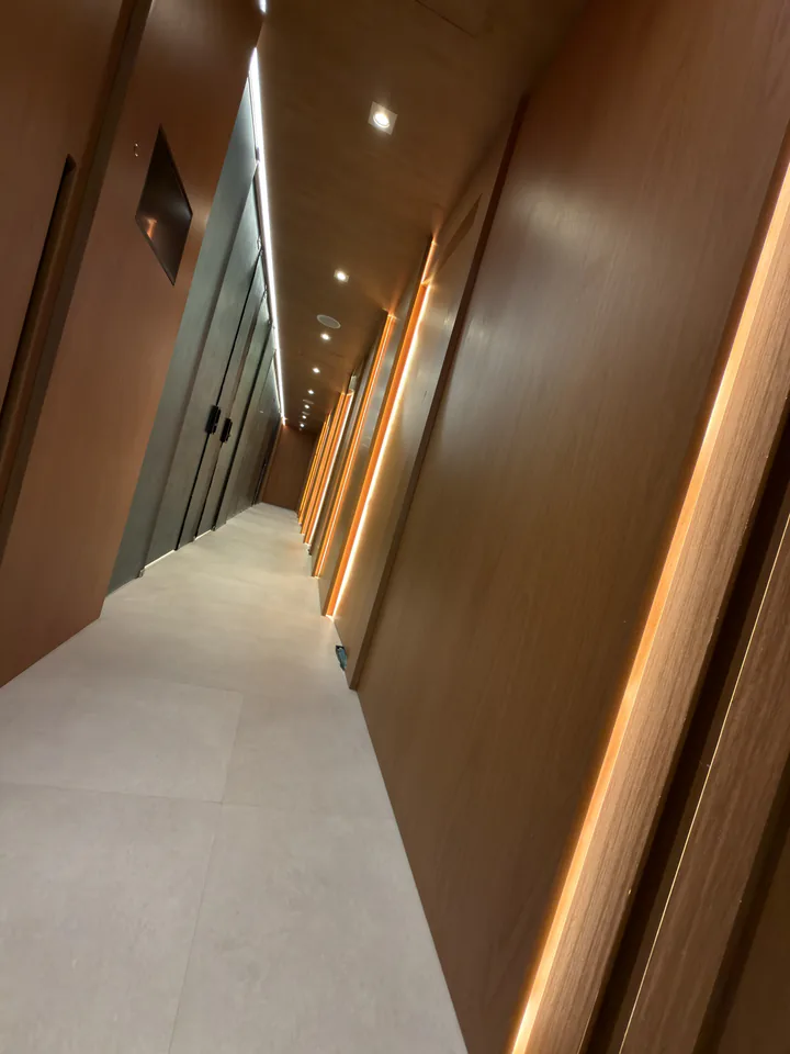 Corredor de madeira com porta de vidro e sequência de luzes quentes