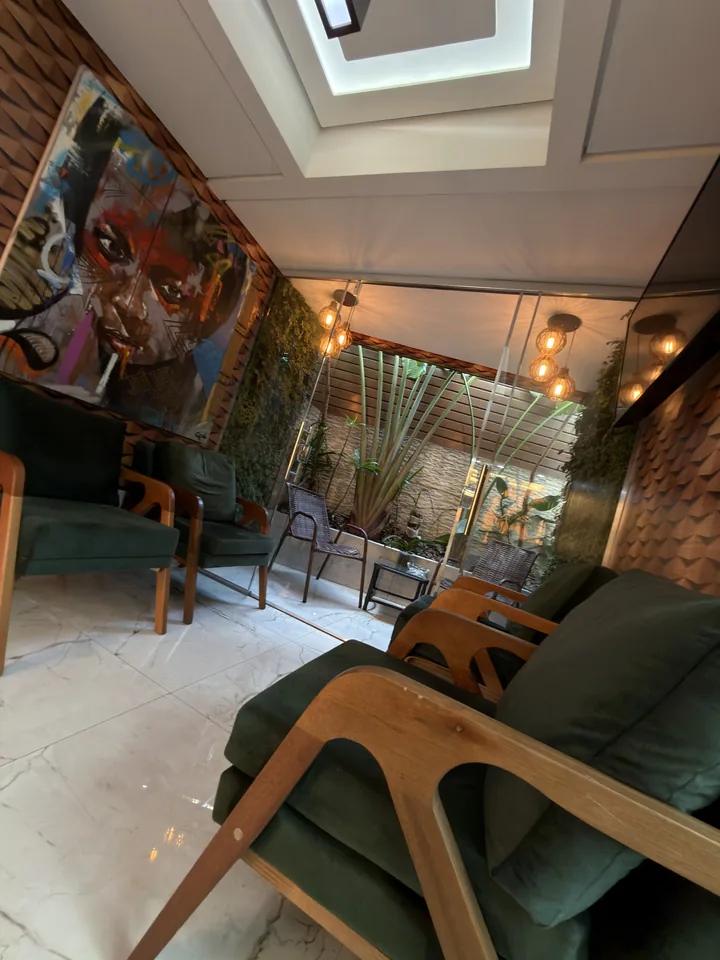 Vista vertical do lounge com poltronas, vegetação e iluminação quente