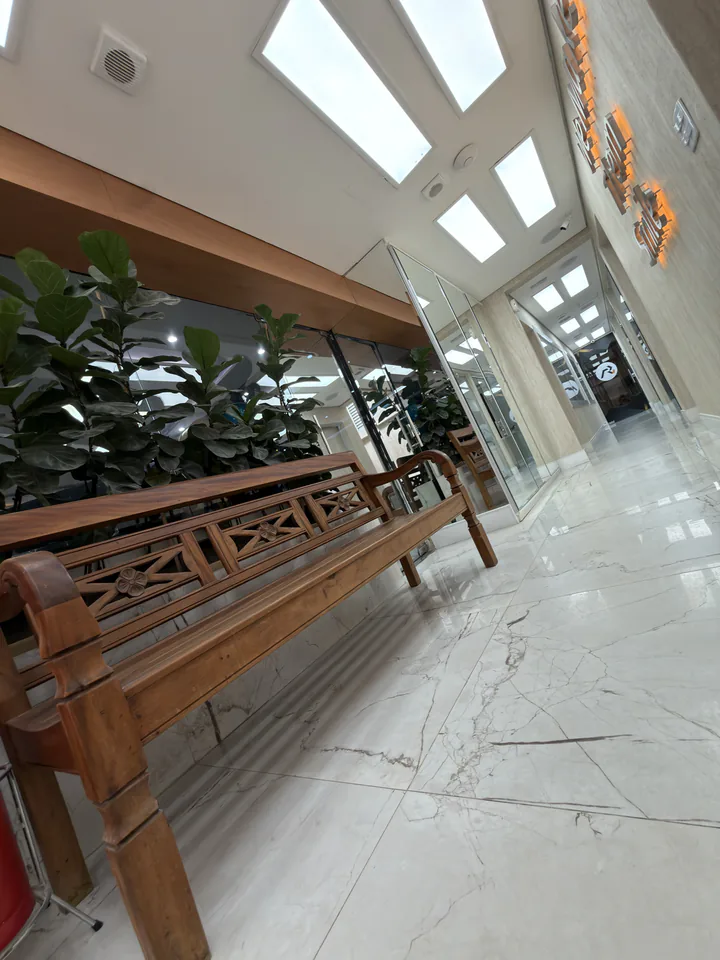 Banco entalhado, plantas e espelhos ao longo de uma passagem interna do Instituto
