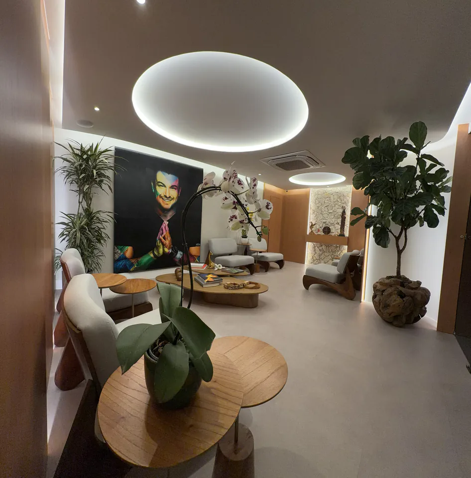 Sala de espera com orquídea em primeiro plano, retrato de Rafa Puglisi e poltronas claras