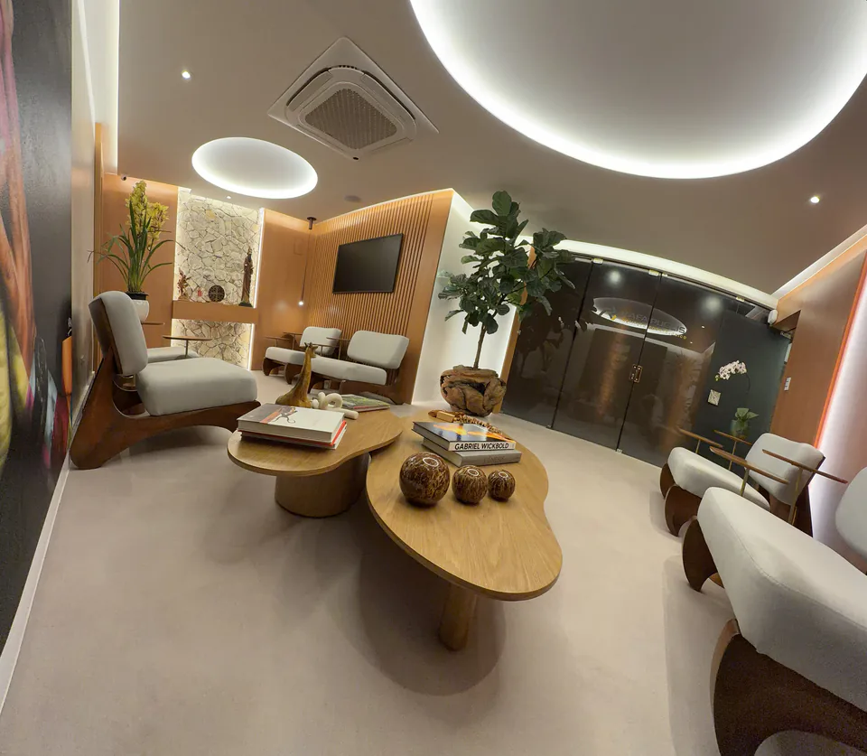 Sala de espera com mesa orgânica central, poltronas claras e vegetação