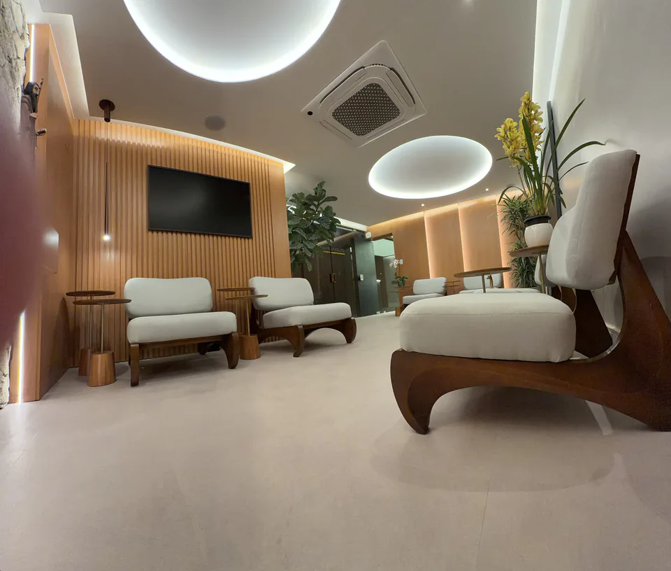 Vista ampla da sala de espera com poltronas claras e iluminação indireta