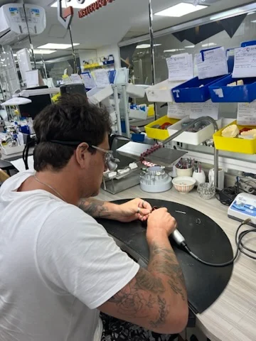 Rafa Puglisi trabalhando sobre uma peça odontológica na bancada do laboratório