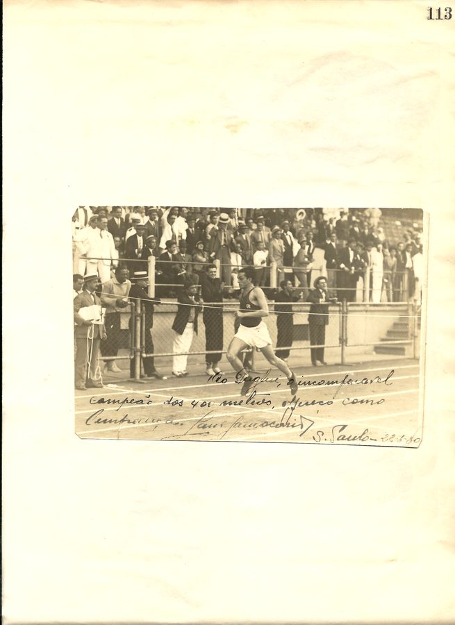 Página de álbum com fotografia de corrida em pista.