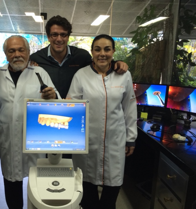 Guy, Rafa e Silvana Puglisi junto a um equipamento odontológico digital.